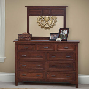 Tall nine-drawer cherry dresser with a wide three-panel mirror styled with photo frames against a tan wall