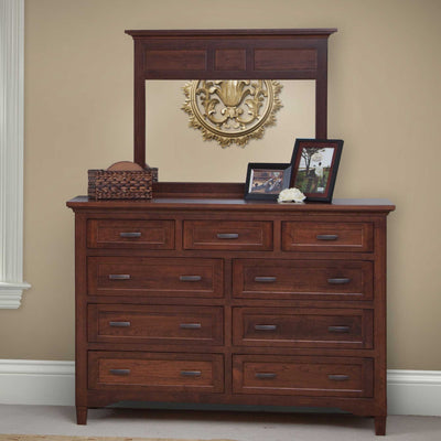 Tall nine-drawer cherry dresser with a wide three-panel mirror styled with photo frames against a tan wall