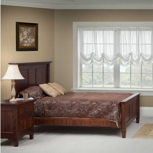 Dark cherry panel bed with nightstand and lamp in a bedroom with brown paisley bedding and sheer curtains