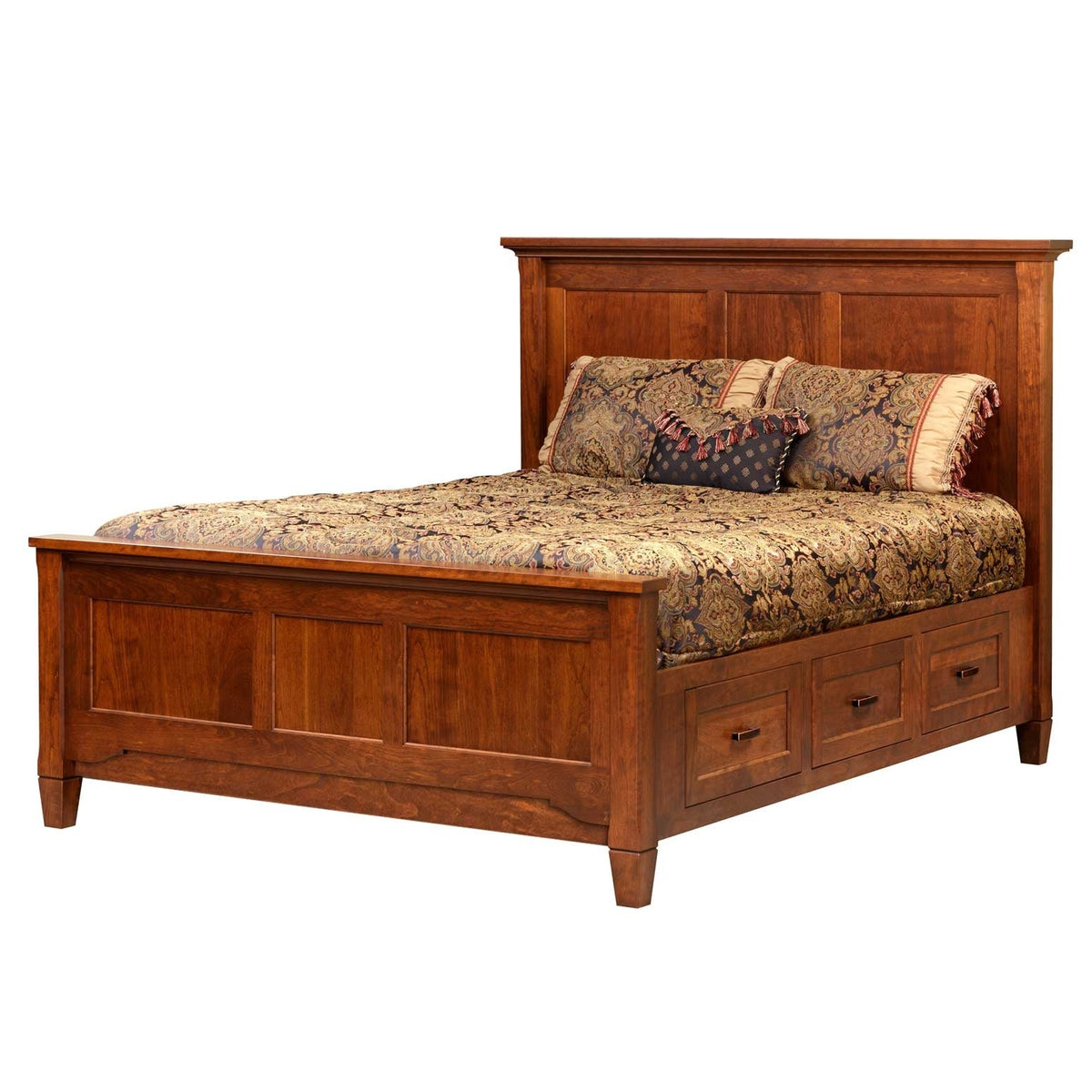 Panel storage bed in medium cherry with three footboard drawers and gold paisley bedding on a white background