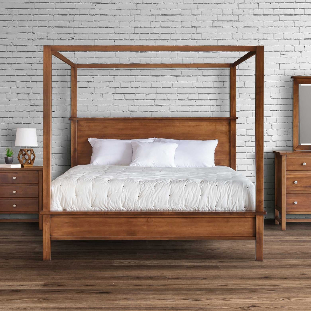 Front view of the wood canopy bed with white bedding flanked by two nightstands in a white brick loft bedroom