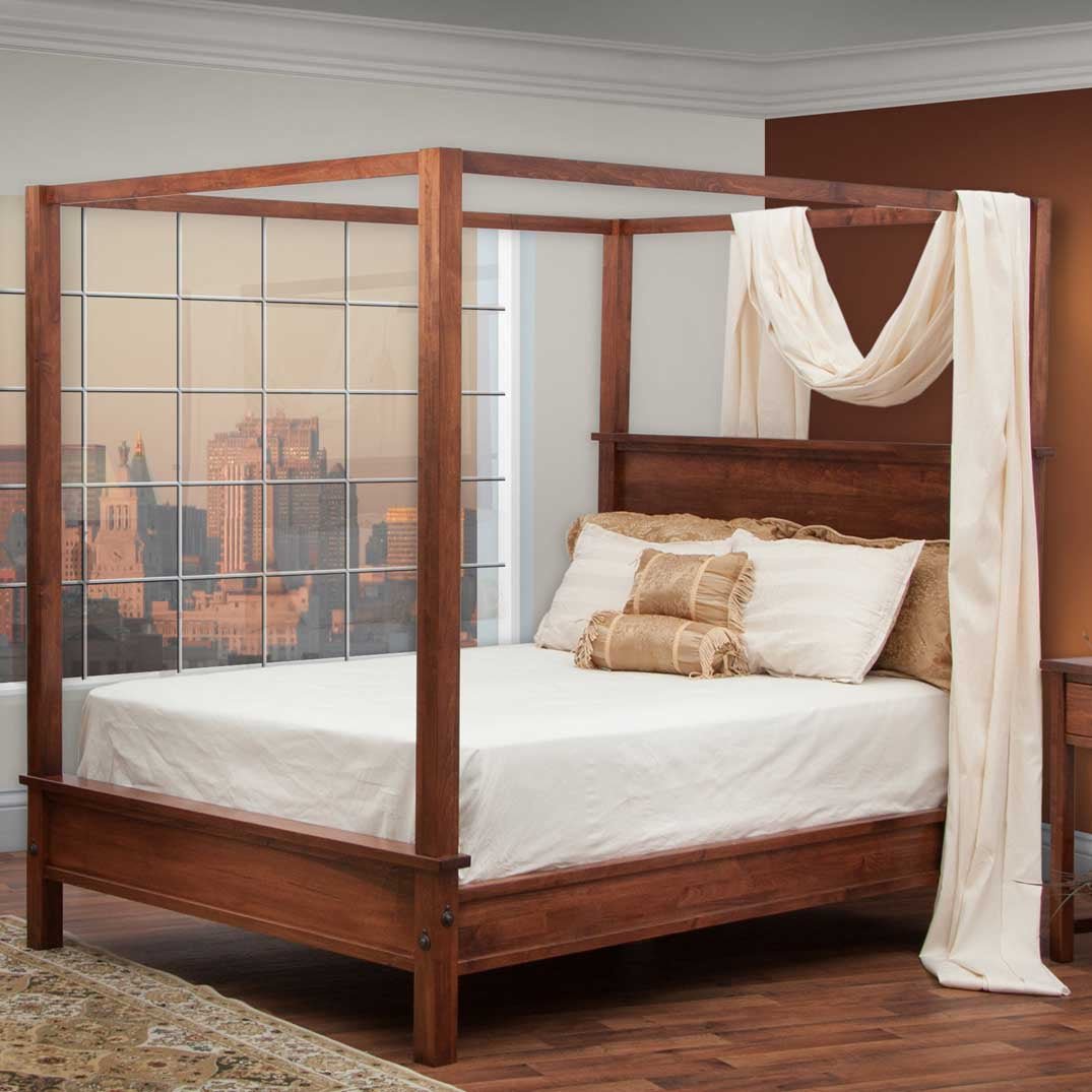 Dark cherry canopy bed draped with a cream fabric swag, styled with gold bedding in a city loft bedroom