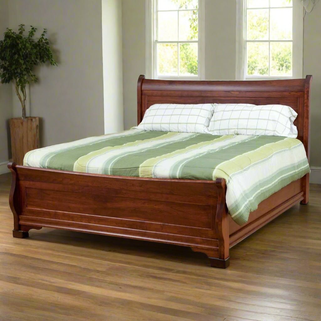 Cherry sleigh bed with curved headboard and footboard, striped green bedding in a room with hardwood floors