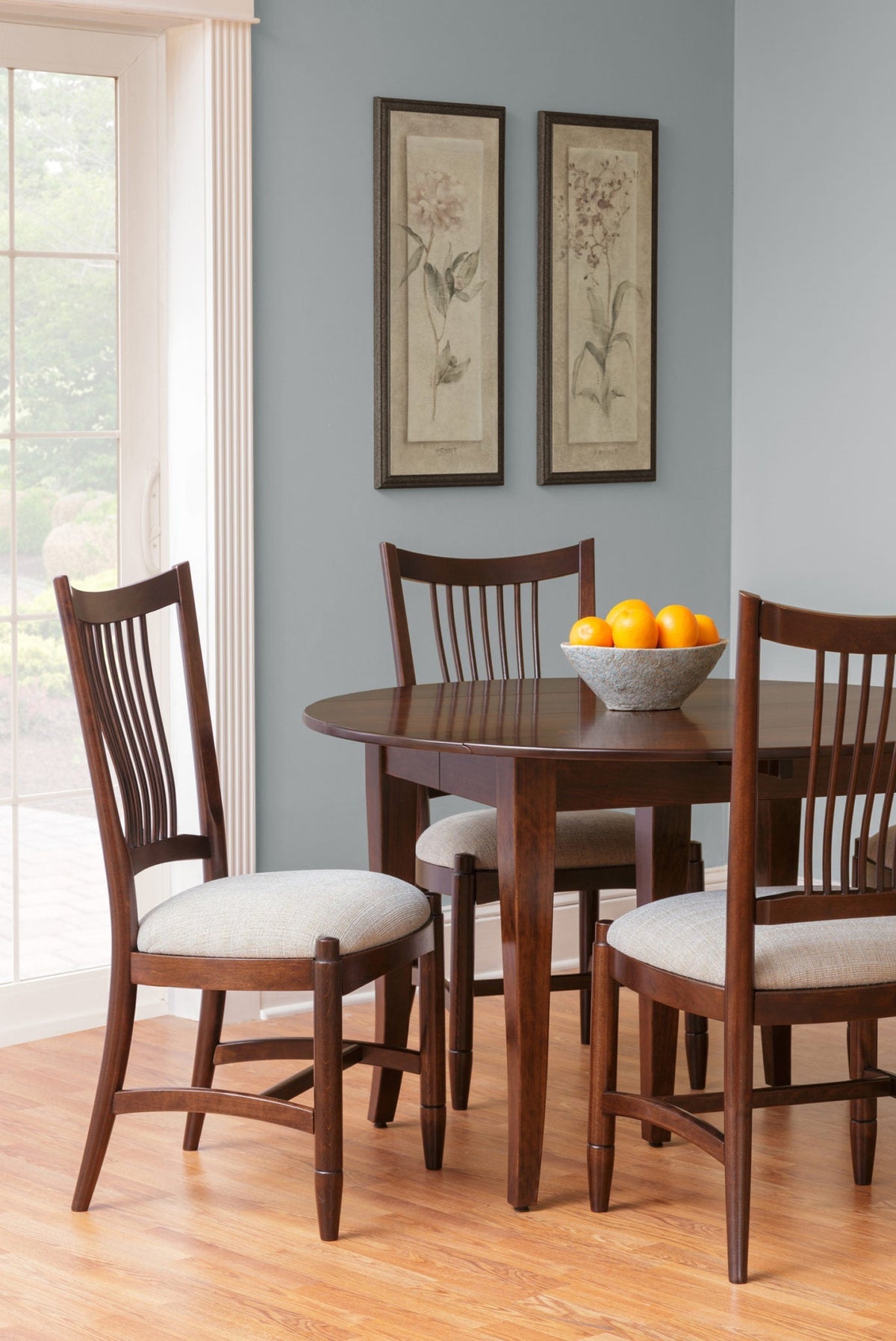 Curved lumbar back dining chairs in dark cherry with cream fabric seats around an oval drop leaf table