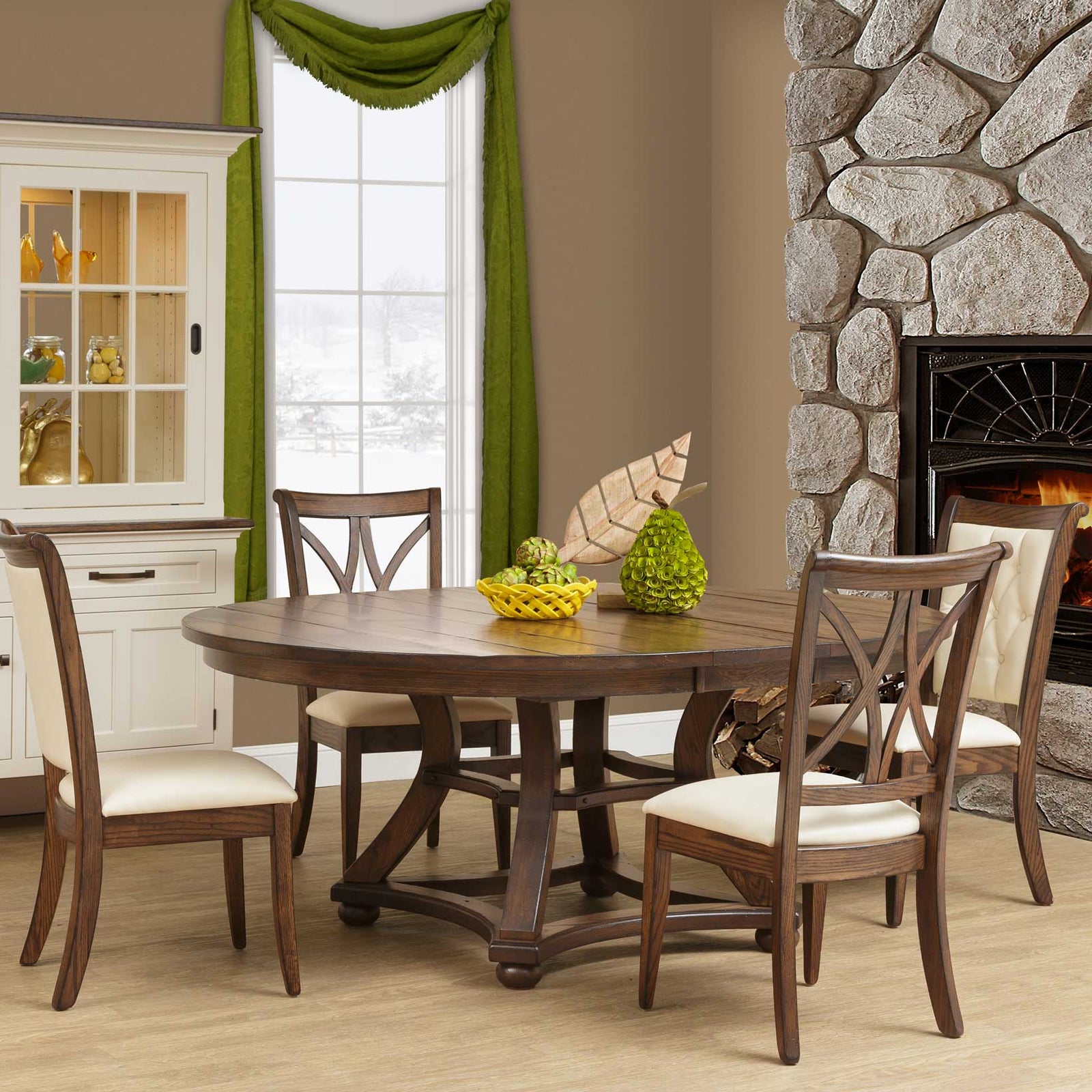 Round expandable dining table in a rustic brown finish with a curved trestle base and four upholstered chairs