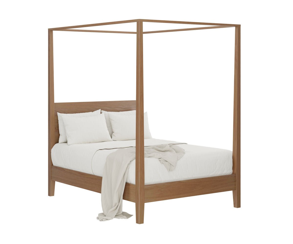Light oak canopy bed with tall square posts and a slim frame, dressed in white linens under a beamed wood ceiling