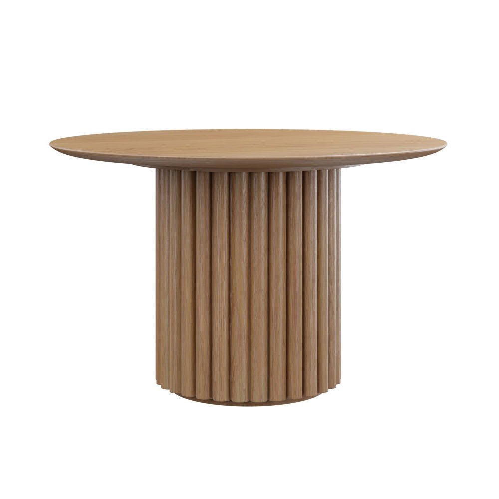 Round pedestal dining table with a fluted column base and curved cream upholstered chairs in a bright dining room