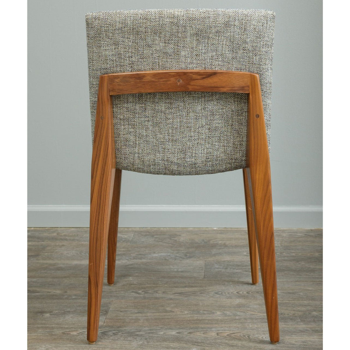 Rear view of a cherry-framed dining chair with oatmeal tweed upholstery and splayed tapered legs