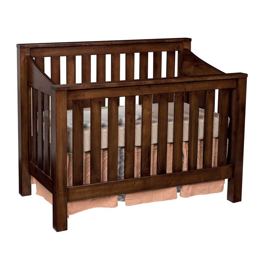 Walnut brown mission crib with tall vertical slats, angled side tops and a pink crib skirt