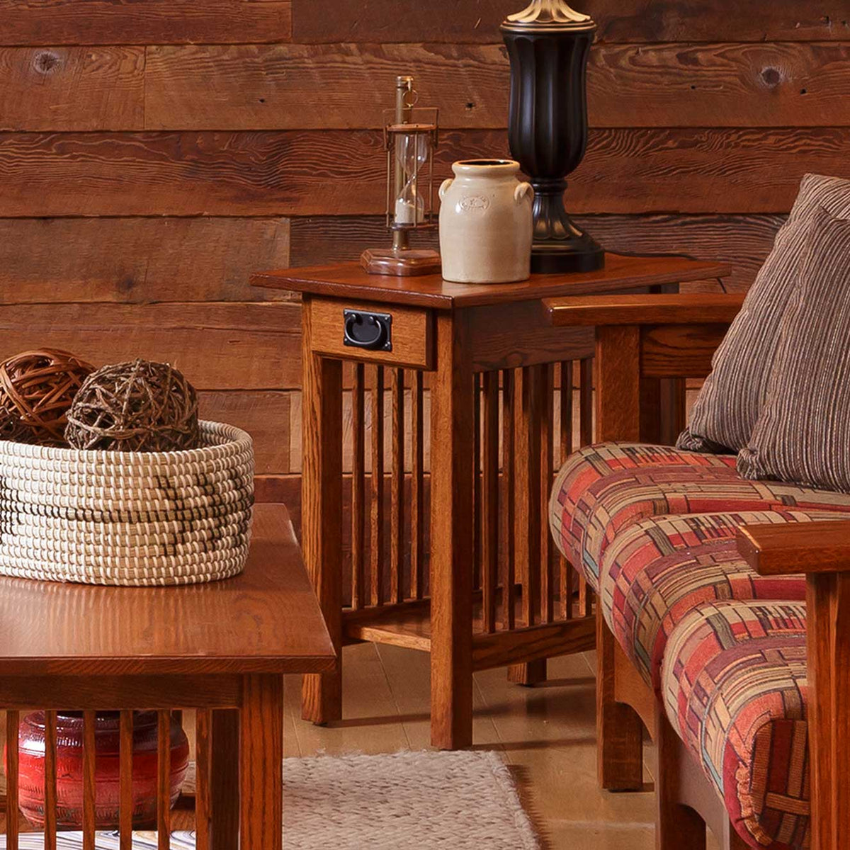 Cherry finish Mission chairside table with drawer and slat sides topped with crocks and a lamp against barnwood walls