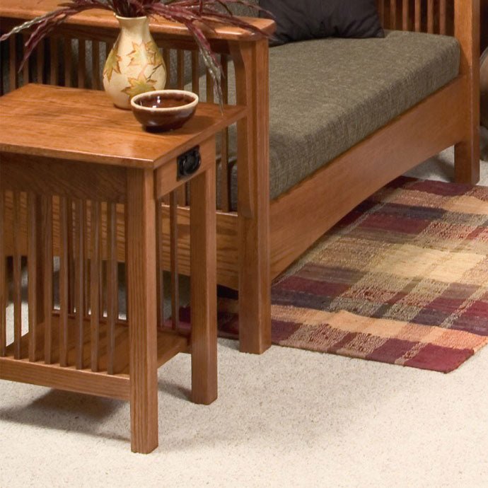 Close-up of an oak Mission end table with black hardware and spindle sides next to a slat arm loveseat