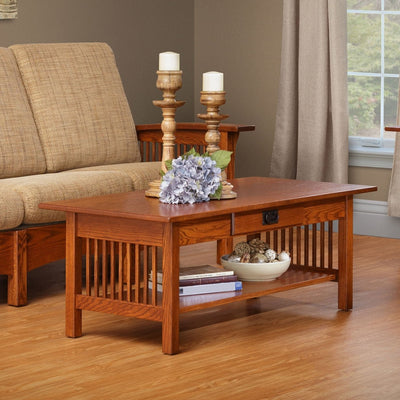 Oak Mission coffee table with a center drawer, spindle sides and lower display shelf holding books and a bowl