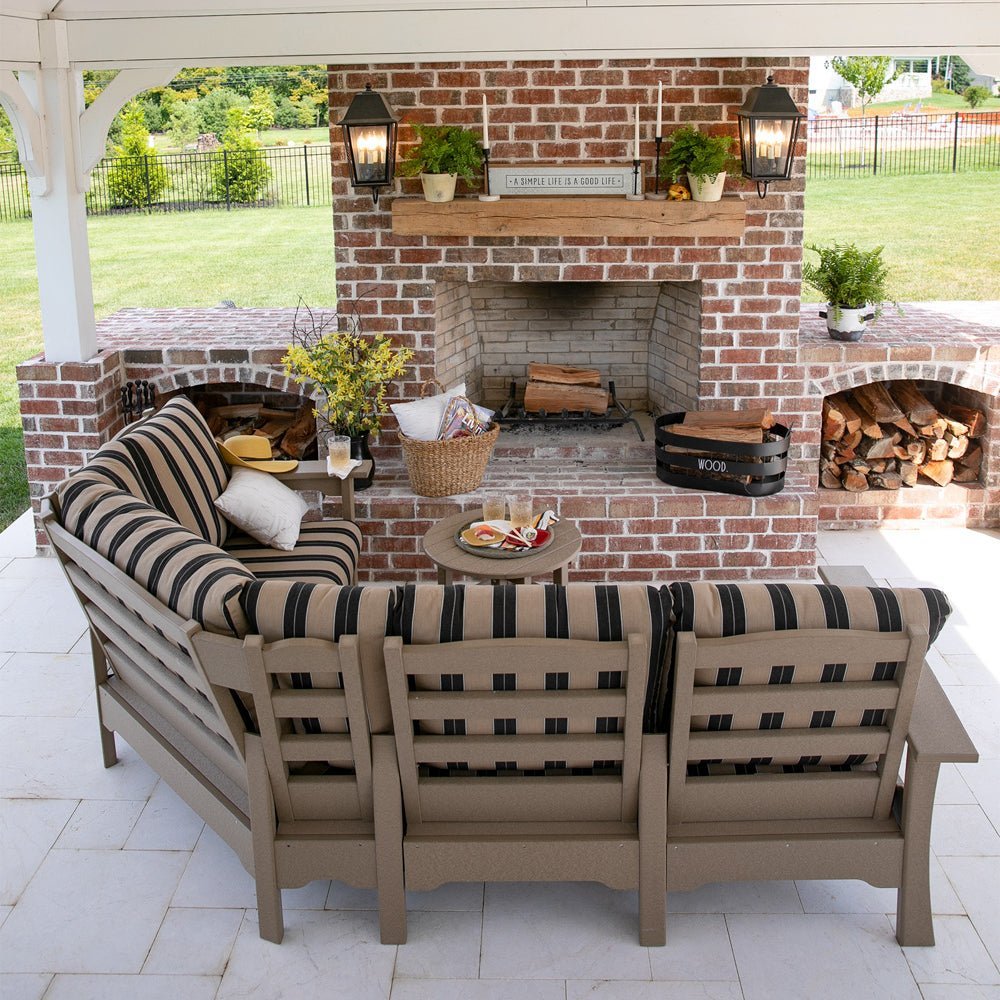 Weathered wood poly corner sectional sofa with black and tan striped cushions and a round side table under a pavilion