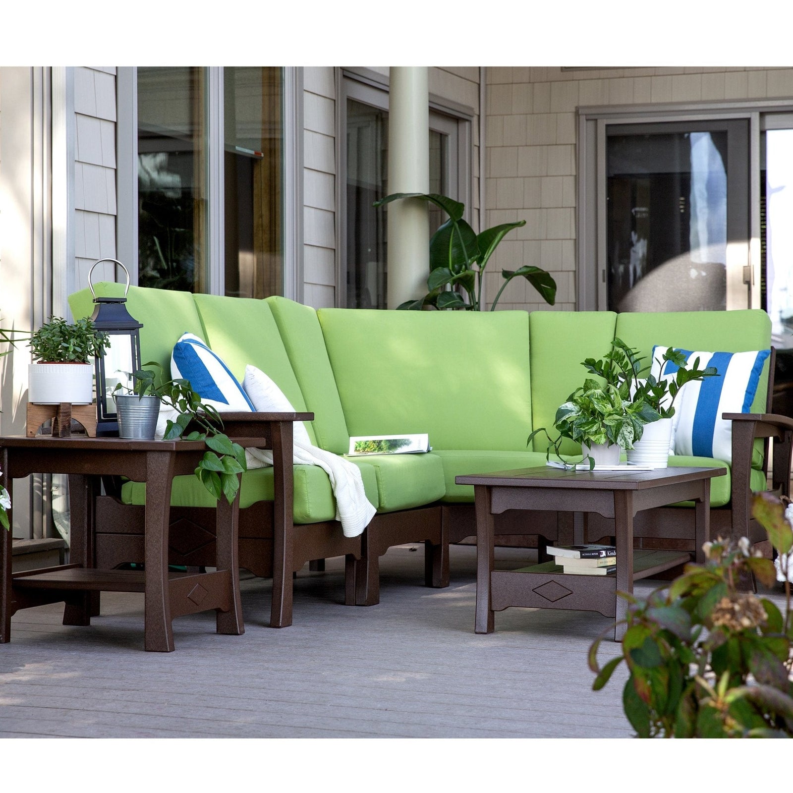 Brown poly corner sofa set with bright green cushions, square coffee table and end table on a gray deck