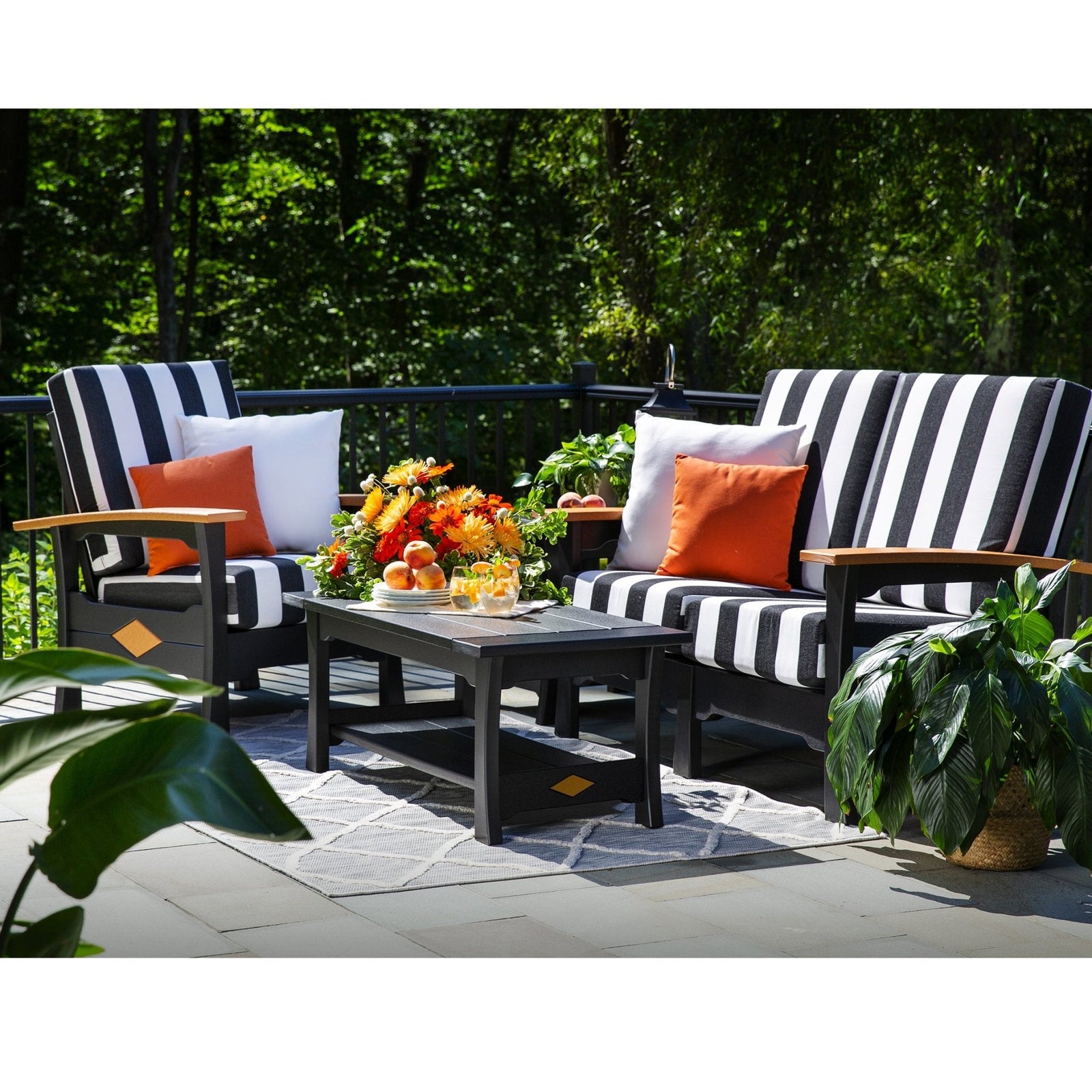 Two black poly loveseats with bold black and white striped cushions and cedar arms around a coffee table on a patio