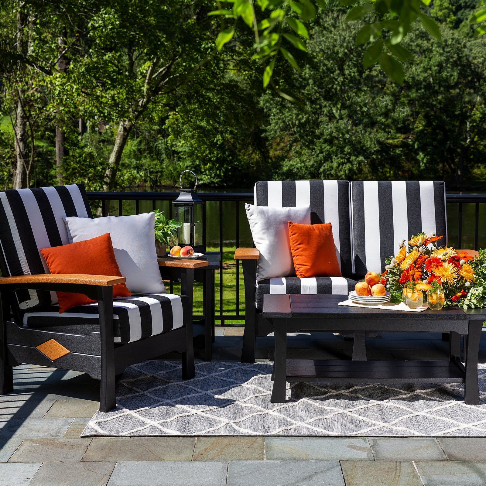 Two black poly loveseats with bold black and white striped cushions and cedar arms around a coffee table on a patio