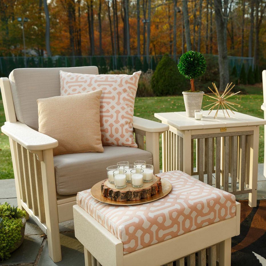 Ivory poly Mission cushion patio chair with tan pillows beside a matching side table and ottoman