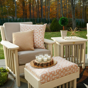 Ivory poly Mission cushion patio chair with tan pillows beside a matching side table and ottoman