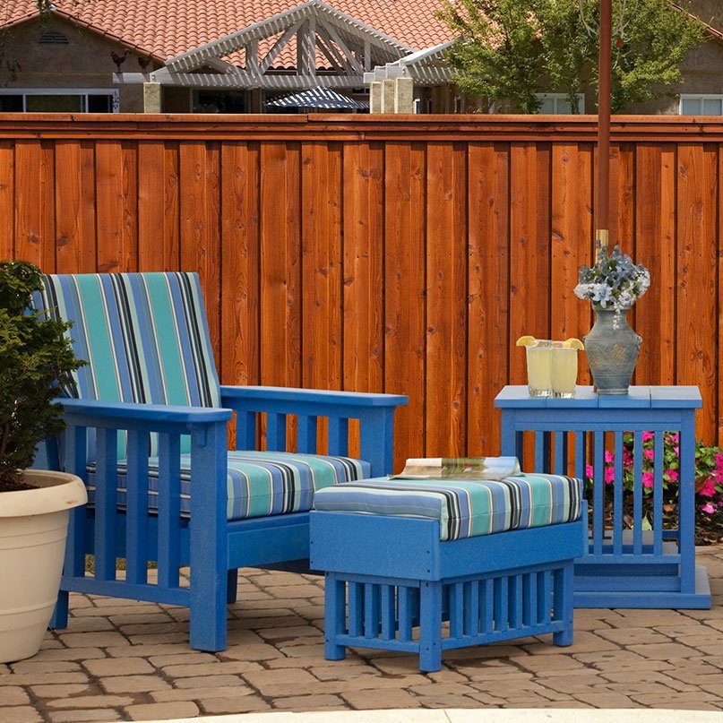Blue poly Mission patio chair with striped cushions, matching ottoman and side table on a paver patio