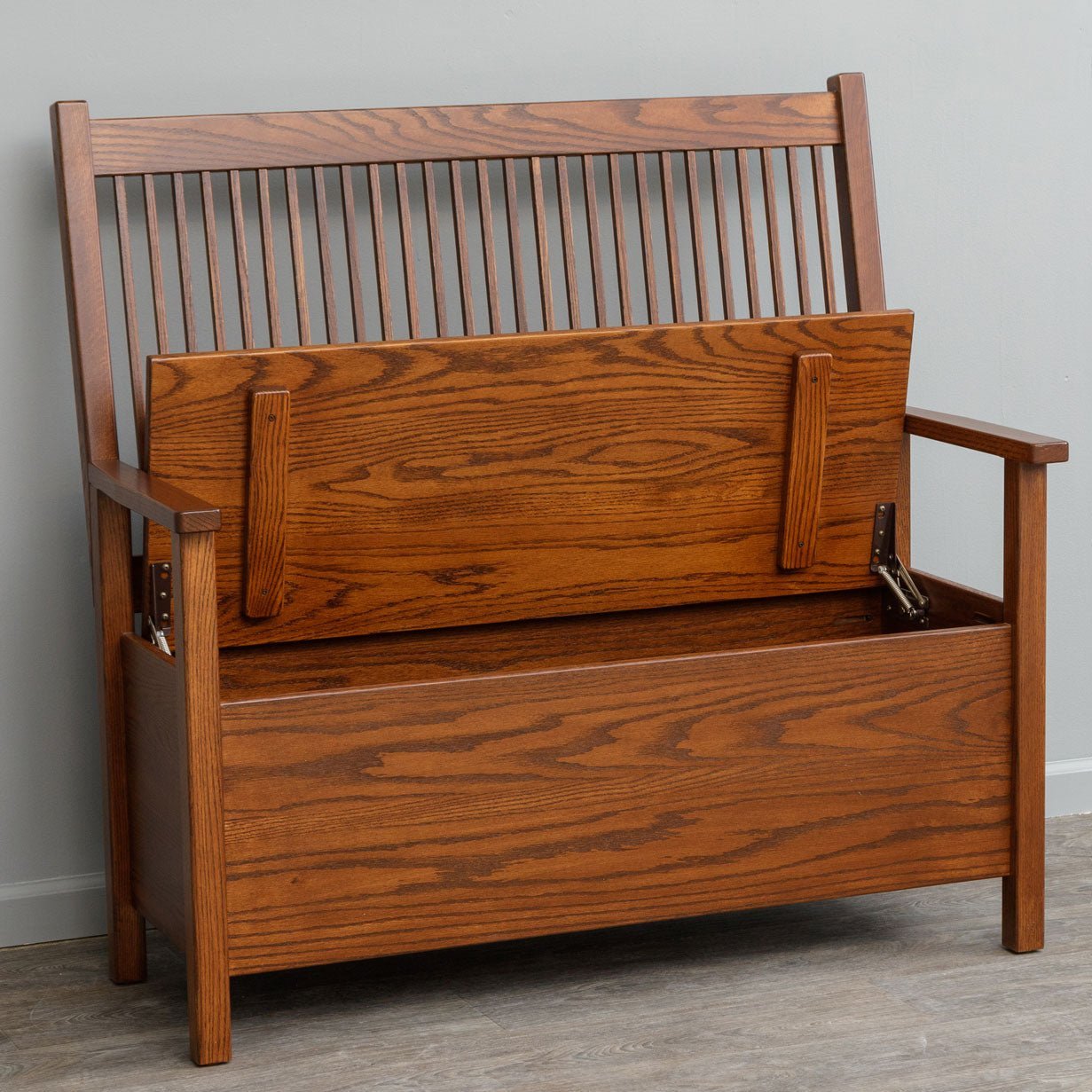 Oak Mission deacon bench with a tall spindle back, flat arms and a hinged lift top storage seat