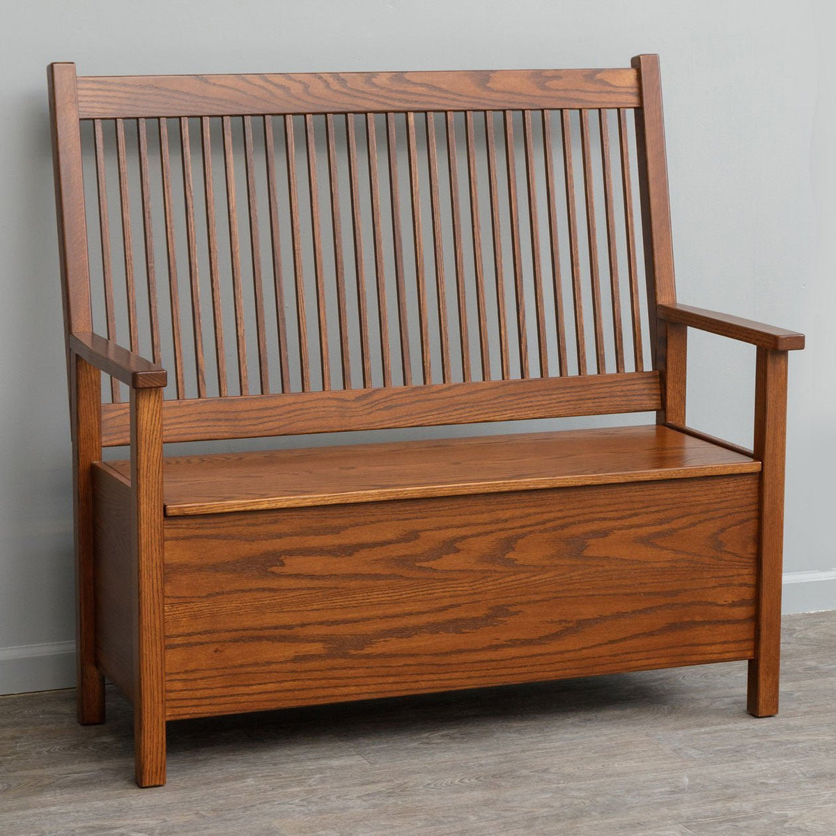 Oak Mission deacon bench with a tall spindle back, flat arms and a hinged lift top storage seat