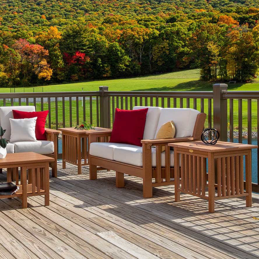 Cedar poly Mission loveseat and chair with white cushions and red pillows on a deck overlooking hills