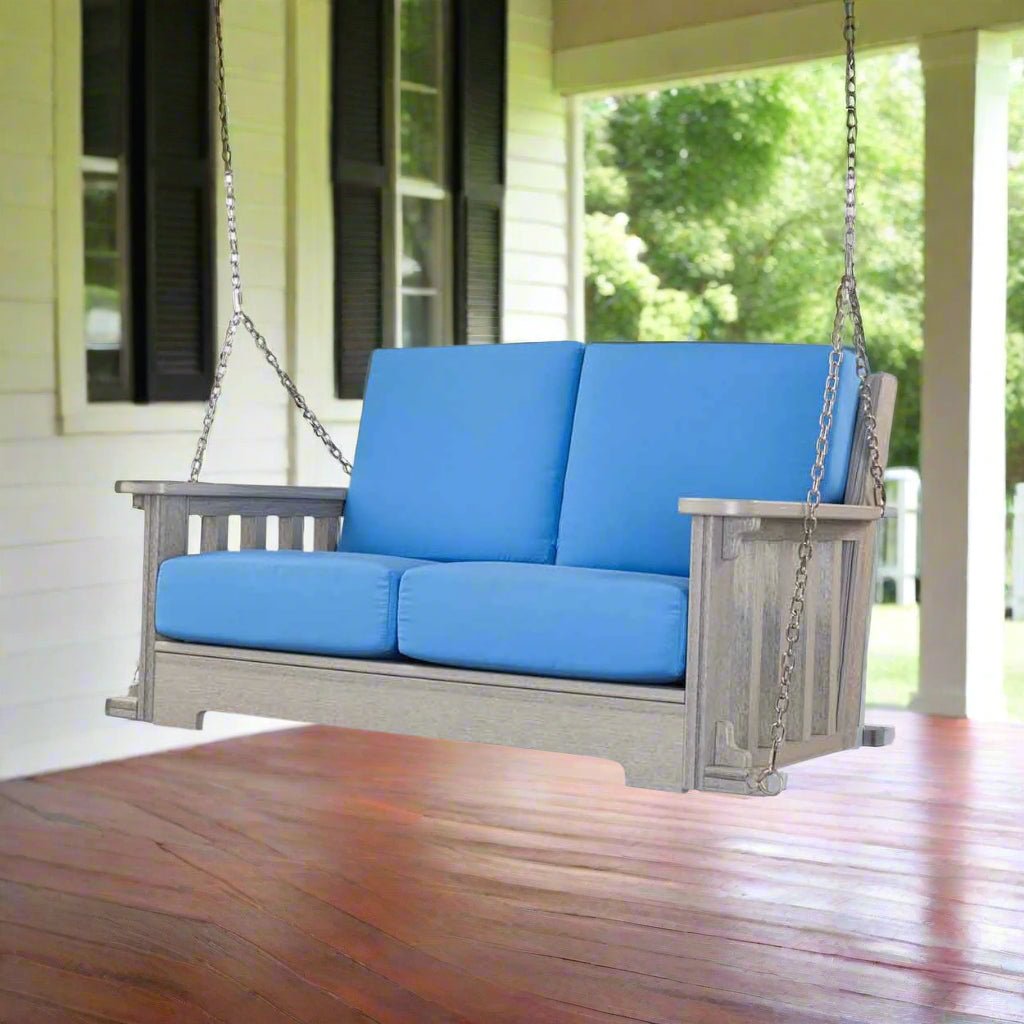 Gray poly Mission porch swing for two with blue cushions hanging from chains on a covered porch