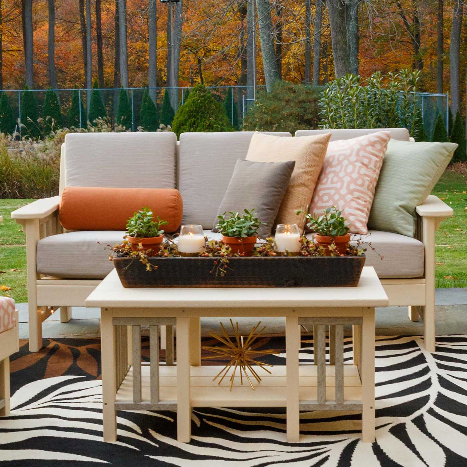 Ivory poly Mission sofa for three with taupe cushions behind a matching slatted coffee table on a rug