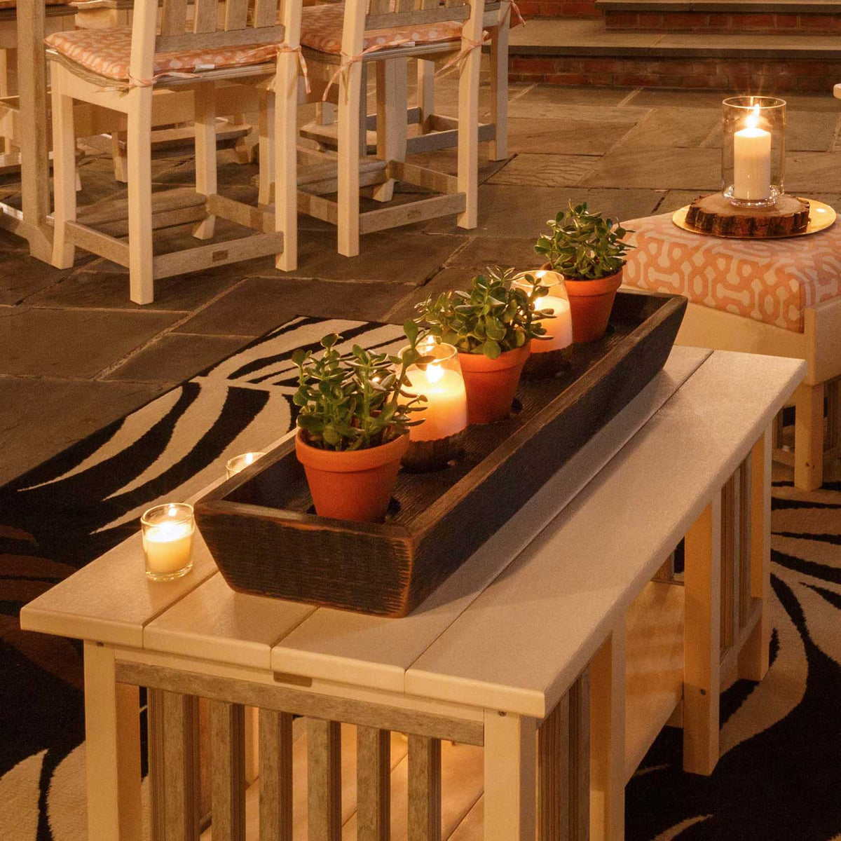 Candlelit ivory poly Mission coffee table with a rustic planter tray on a patio at night