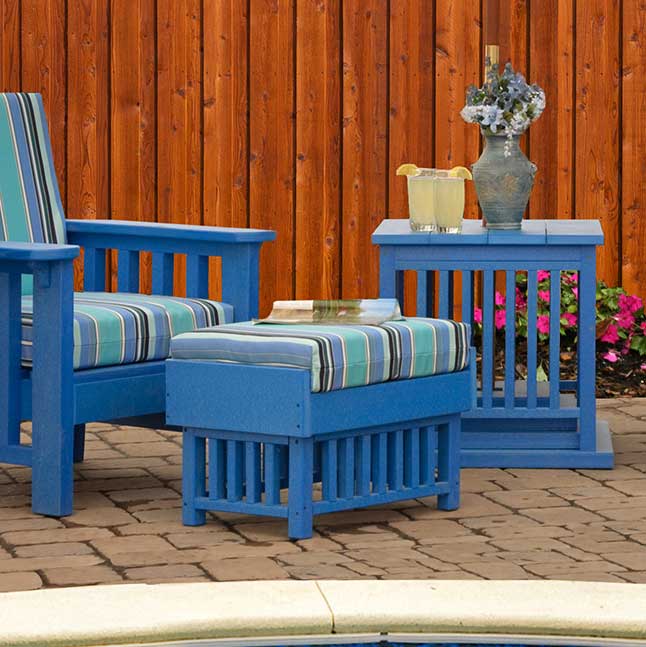Blue poly Mission ottoman with striped cushion beside a matching chair and side table by a pool
