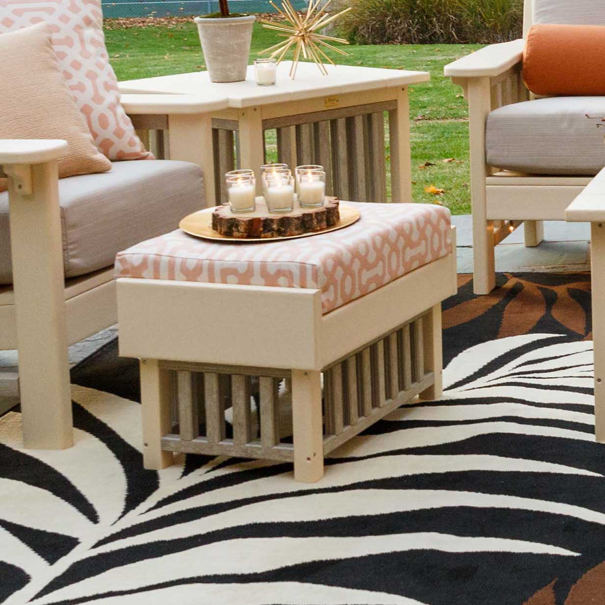 Cream poly Mission ottoman with a patterned cushion and slat sides holding a candle tray on a rug