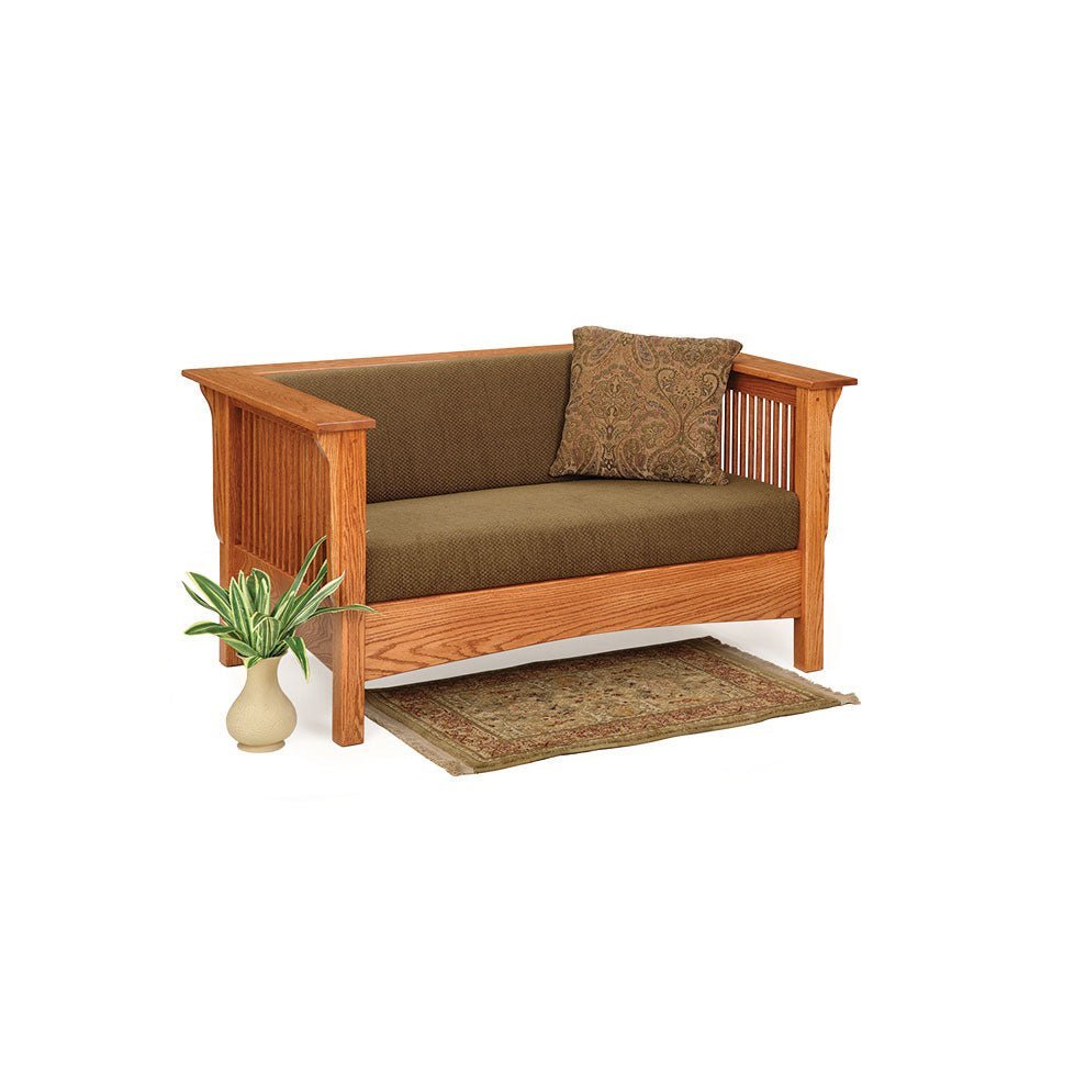 Oak Mission club loveseat with olive cushions, spindle sides and black pillow in a knotty pine living room