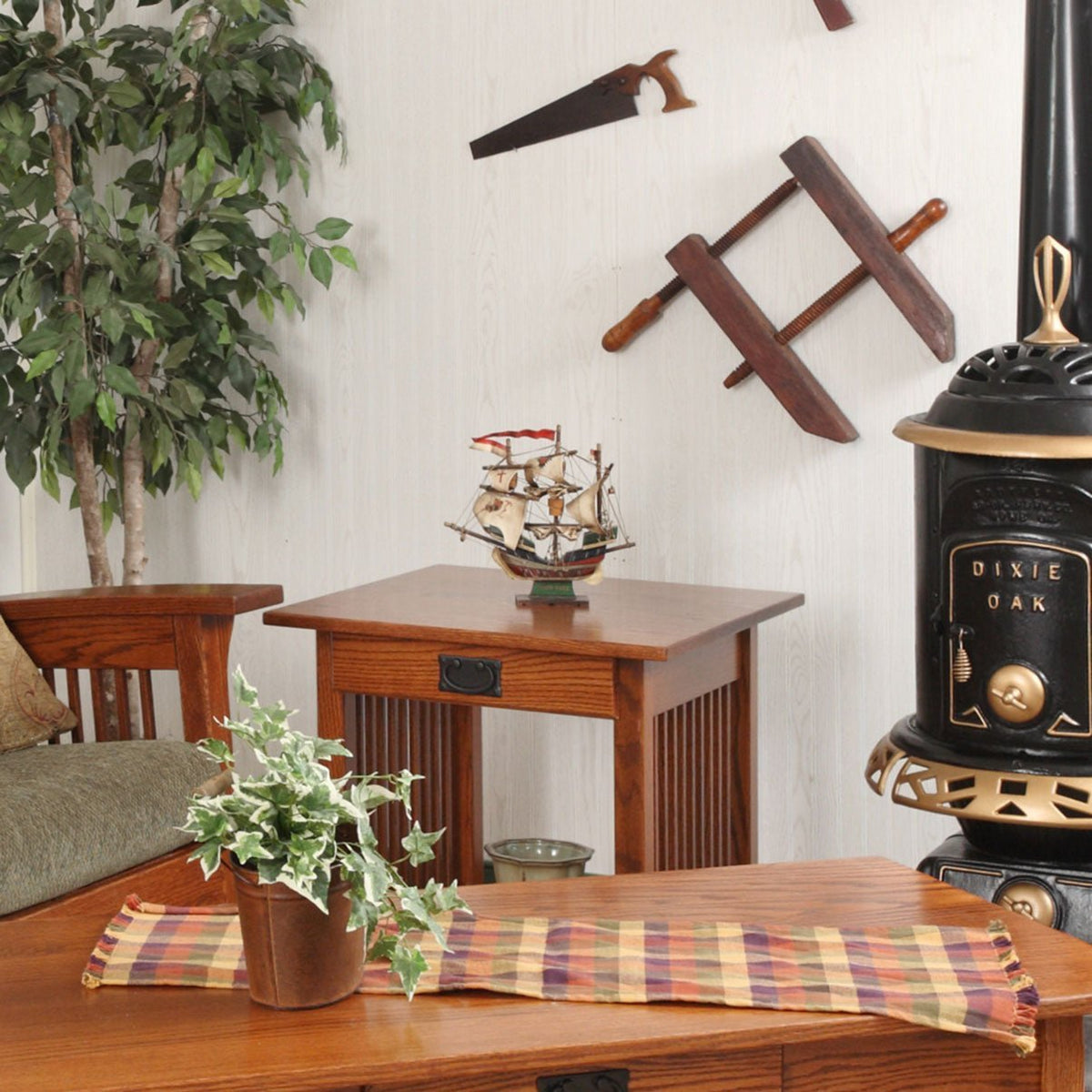 Oak Mission end table with drawer displaying a model ship beside a Mission coffee table and antique parlor stove