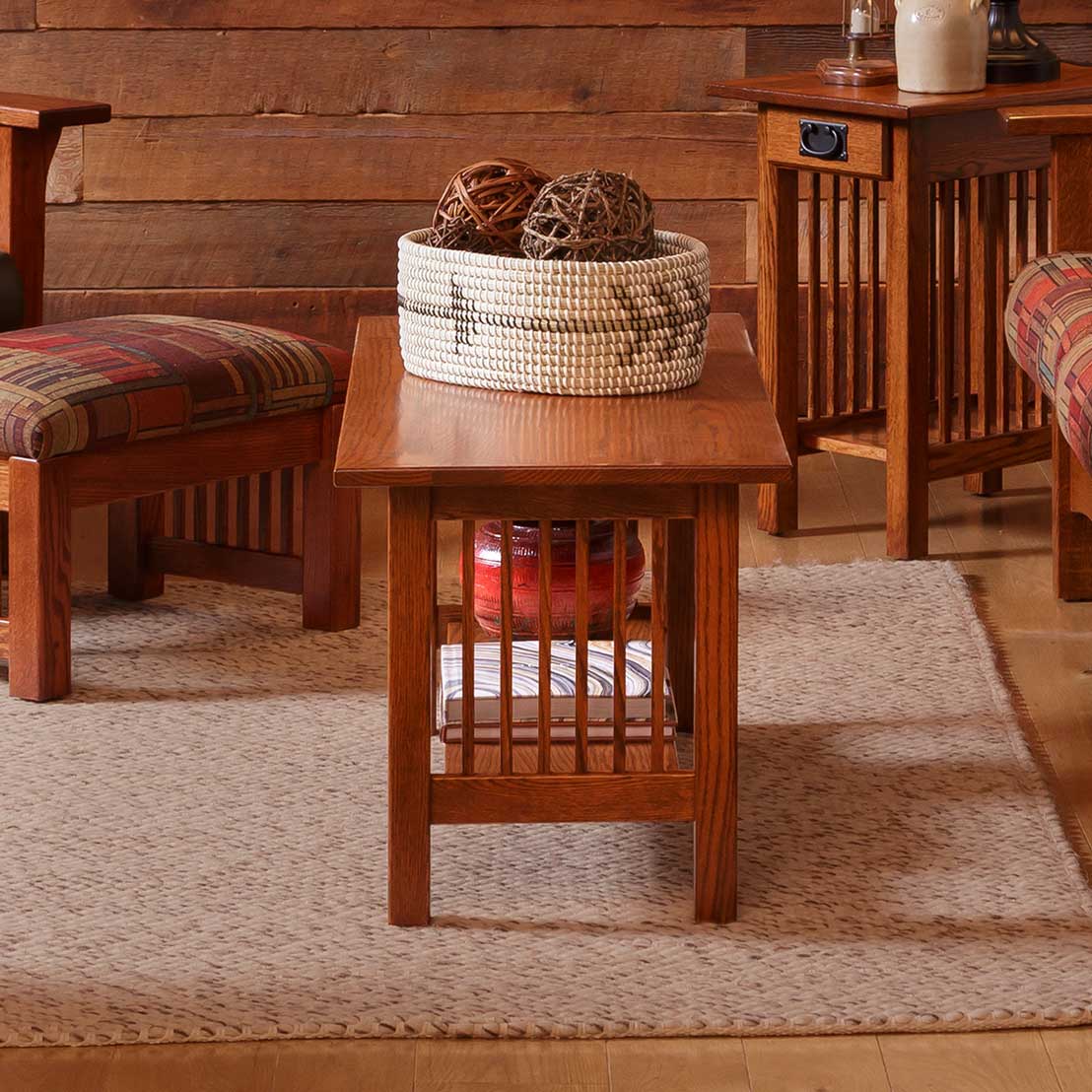 Oak Mission junior coffee table with slat sides and lower shelf holding books and a red crock in a barnwood room