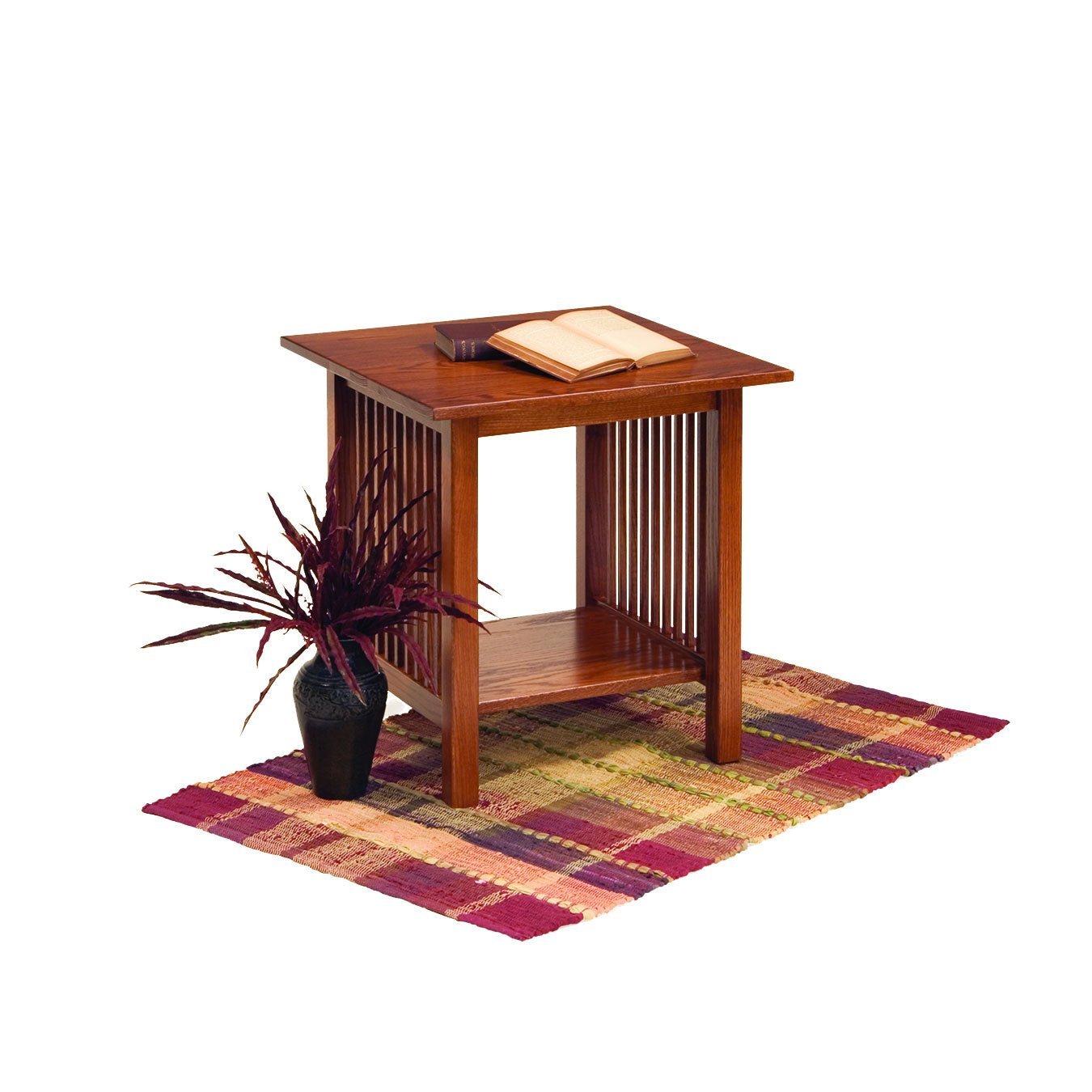 Square Mission oak end table with vertical slat sides and a bottom shelf, open book on top and a plaid rug below
