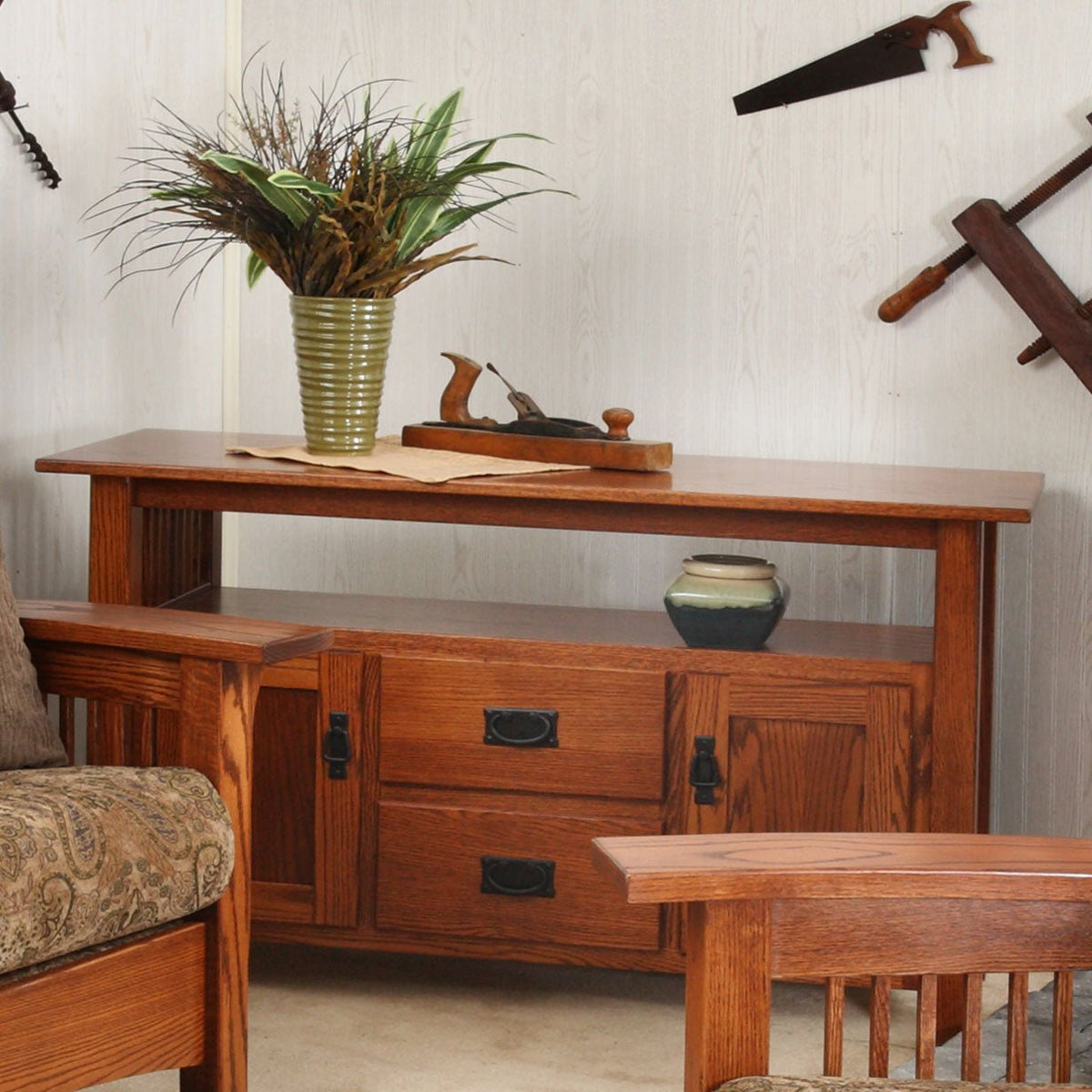 Quartersawn oak entertainment console with two drawers, paneled doors and open shelf under a vase of dried grasses