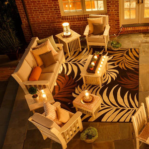 Overhead night view of a cream poly Mission patio sofa set with candles on a patterned outdoor rug