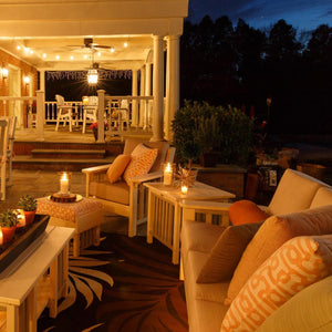 Candlelit ivory poly Mission sofa, chair and side tables on a covered porch at night