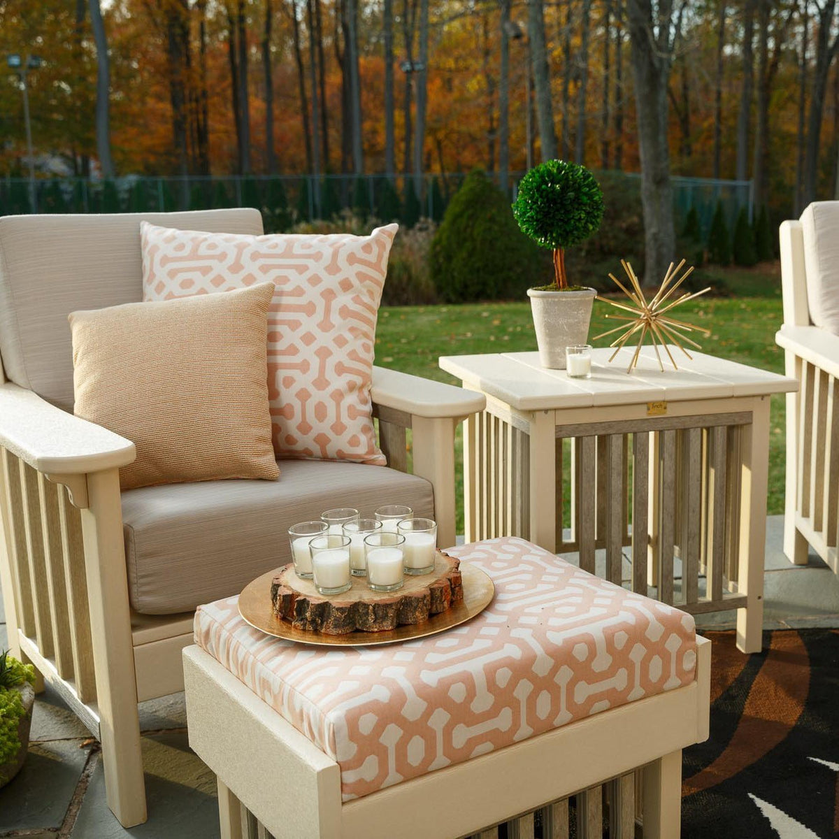 Cream poly Mission chair with taupe cushions next to a side table and patterned ottoman in autumn