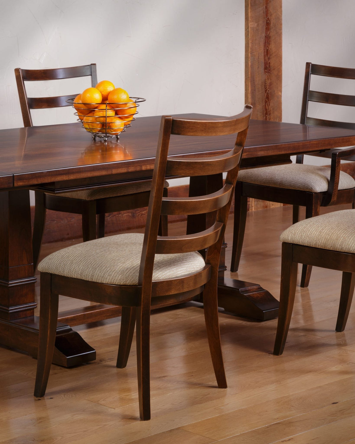 Modern ladder back dining chairs in dark brown with woven oatmeal seats around a trestle dining table