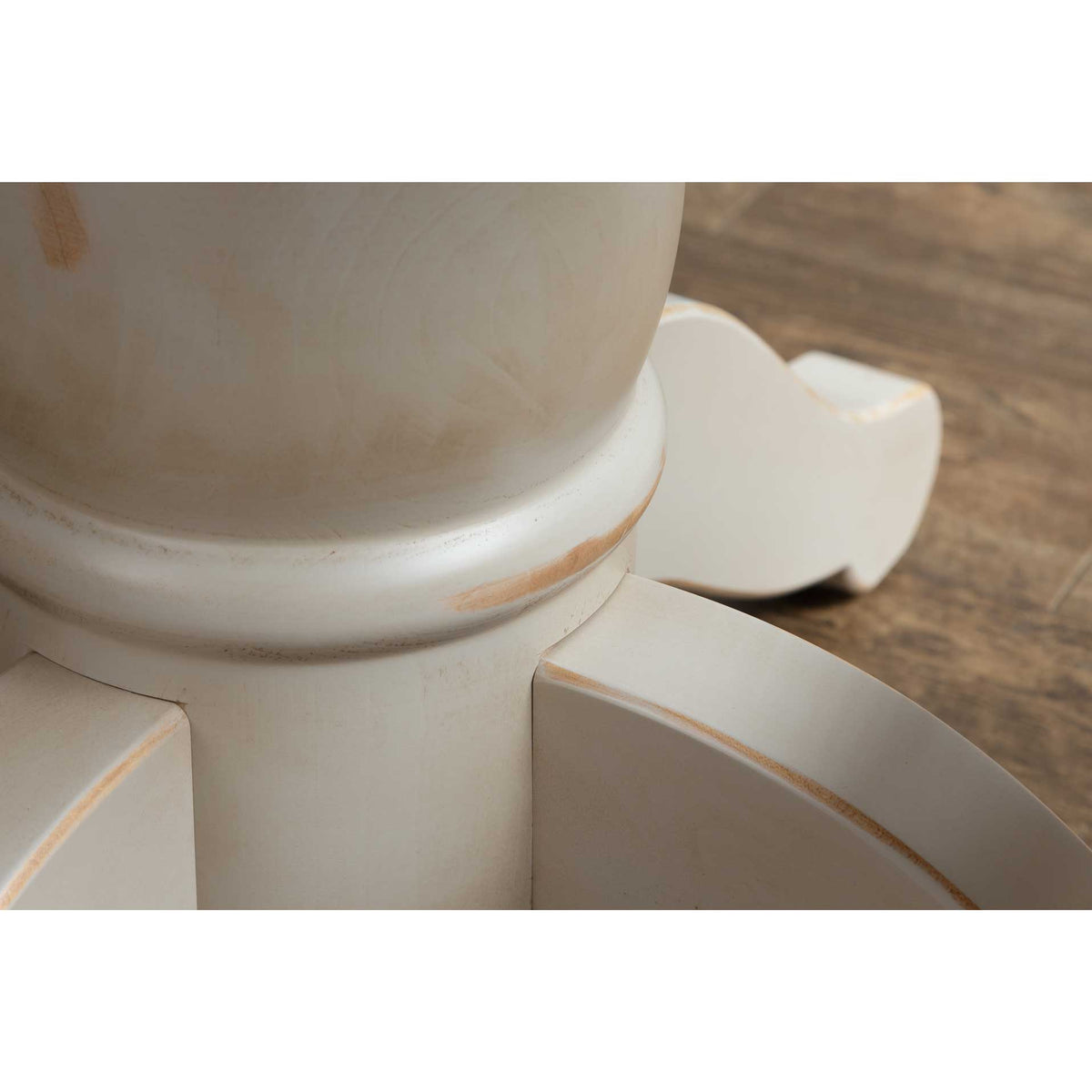 Detail of the antique white pedestal column and scrolled foot showing lightly distressed paint edges