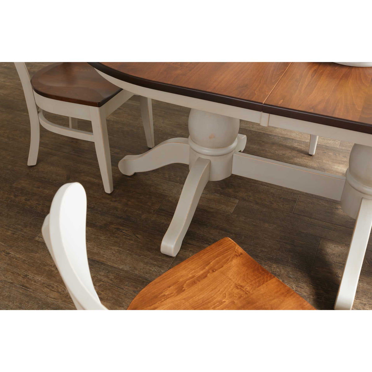 Overhead angle of the oval table's white pedestal base and curved legs with two two-tone chairs