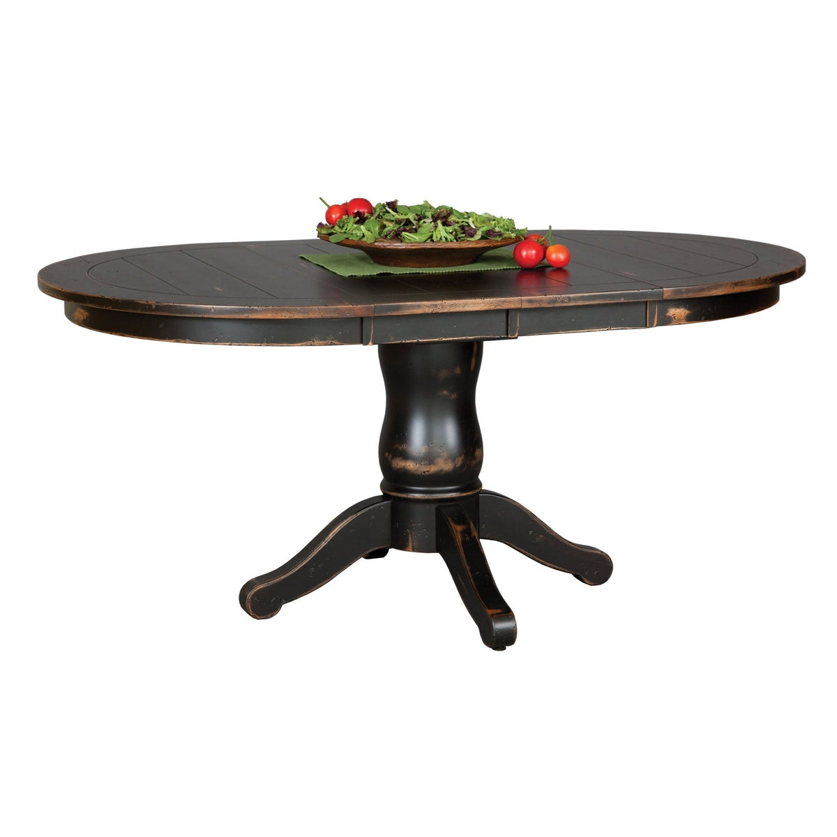 Distressed black round-to-oval pedestal table with the leaf in place, holding a salad bowl and tomatoes