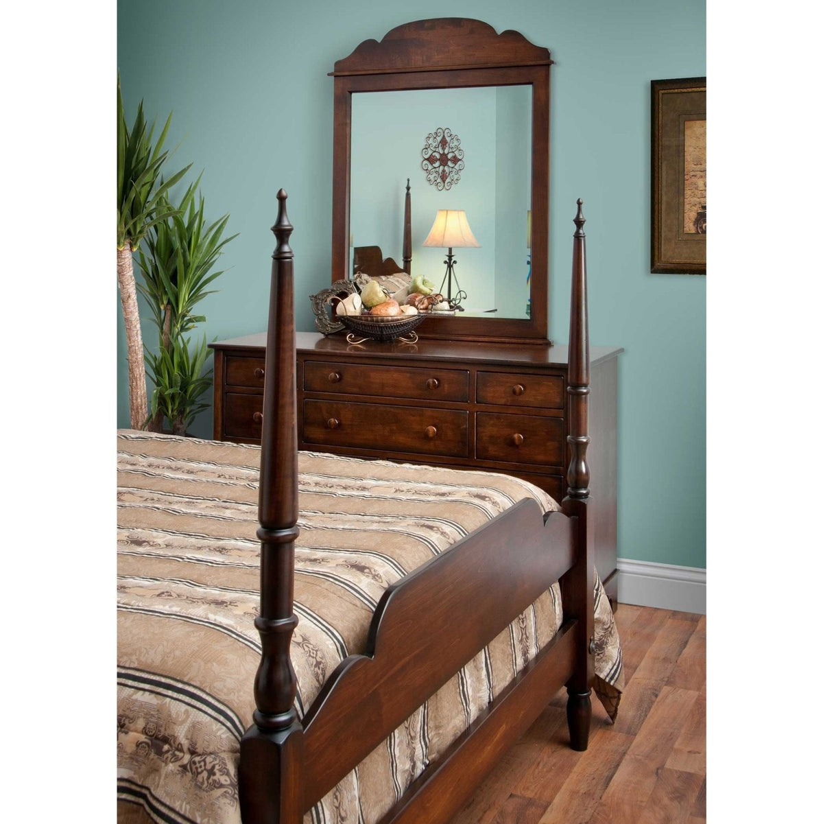 Poster bed footboard in cherry beside a six-drawer dresser and arched mirror against a teal wall