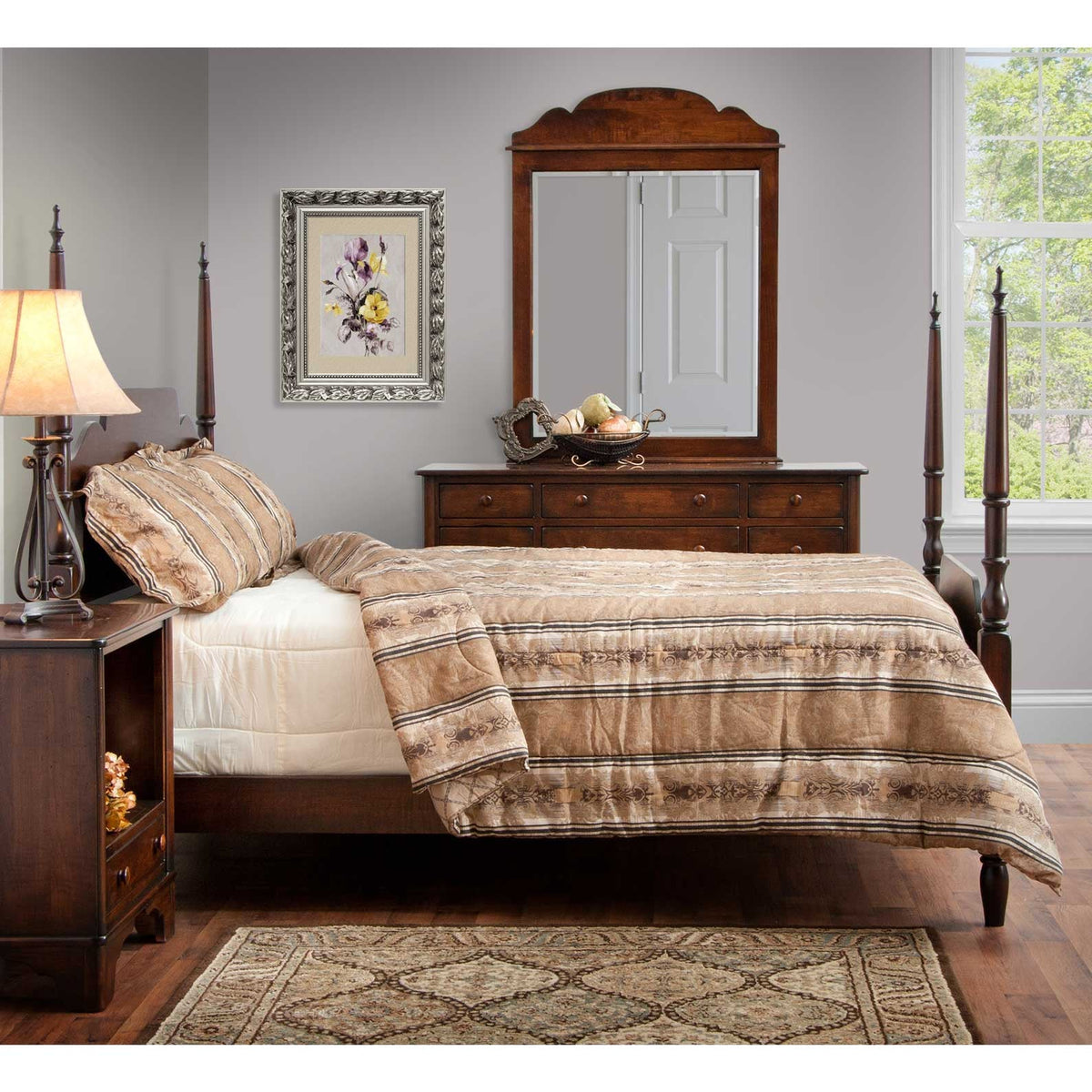 Cherry poster bed with striped bedding facing a dresser with an arch top mirror in a gray walled bedroom