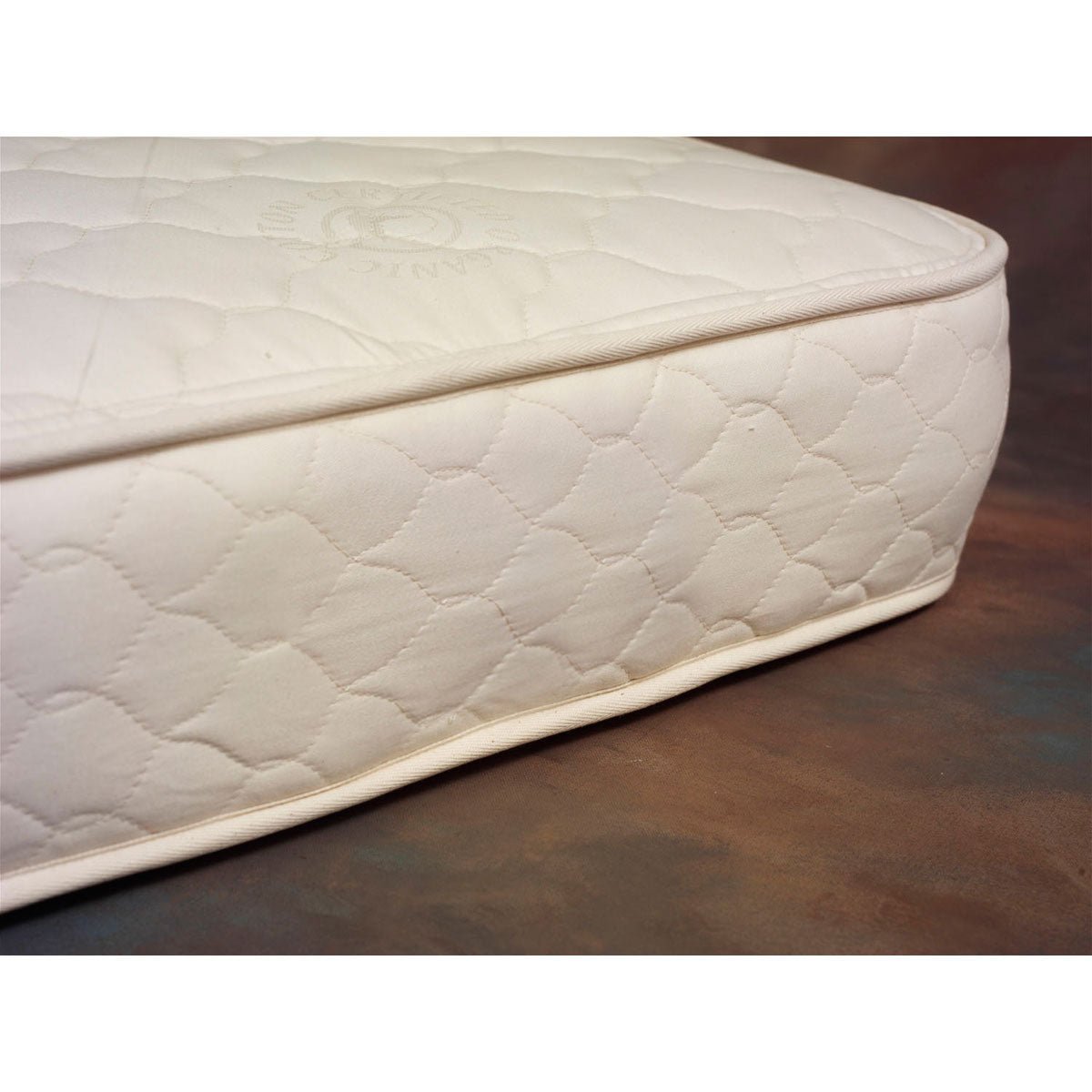 Corner detail of an organic crib mattress with quilted natural cotton cover and piped edges