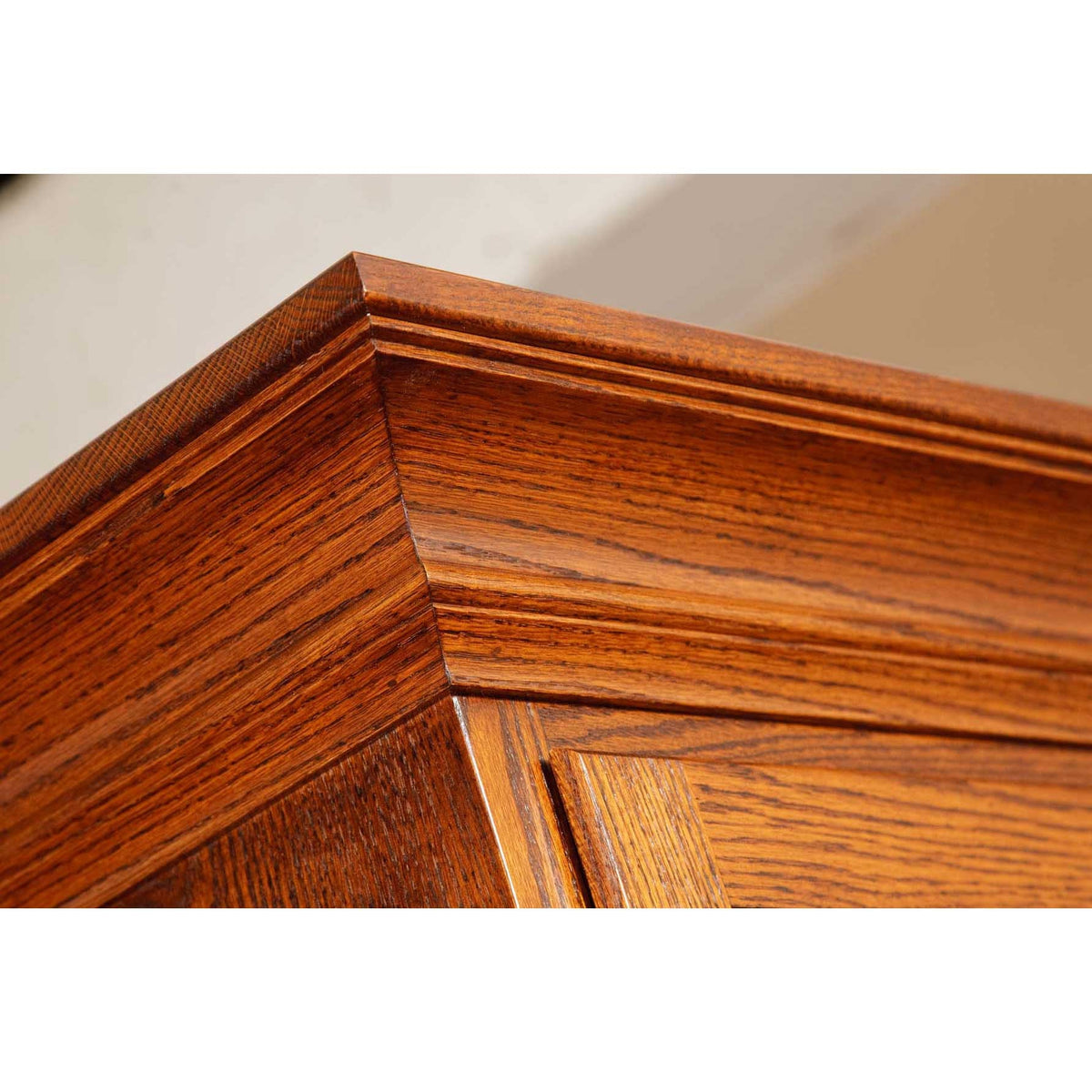 Close-up of the oak desk corner showing layered edge molding and quartersawn grain in a chestnut finish