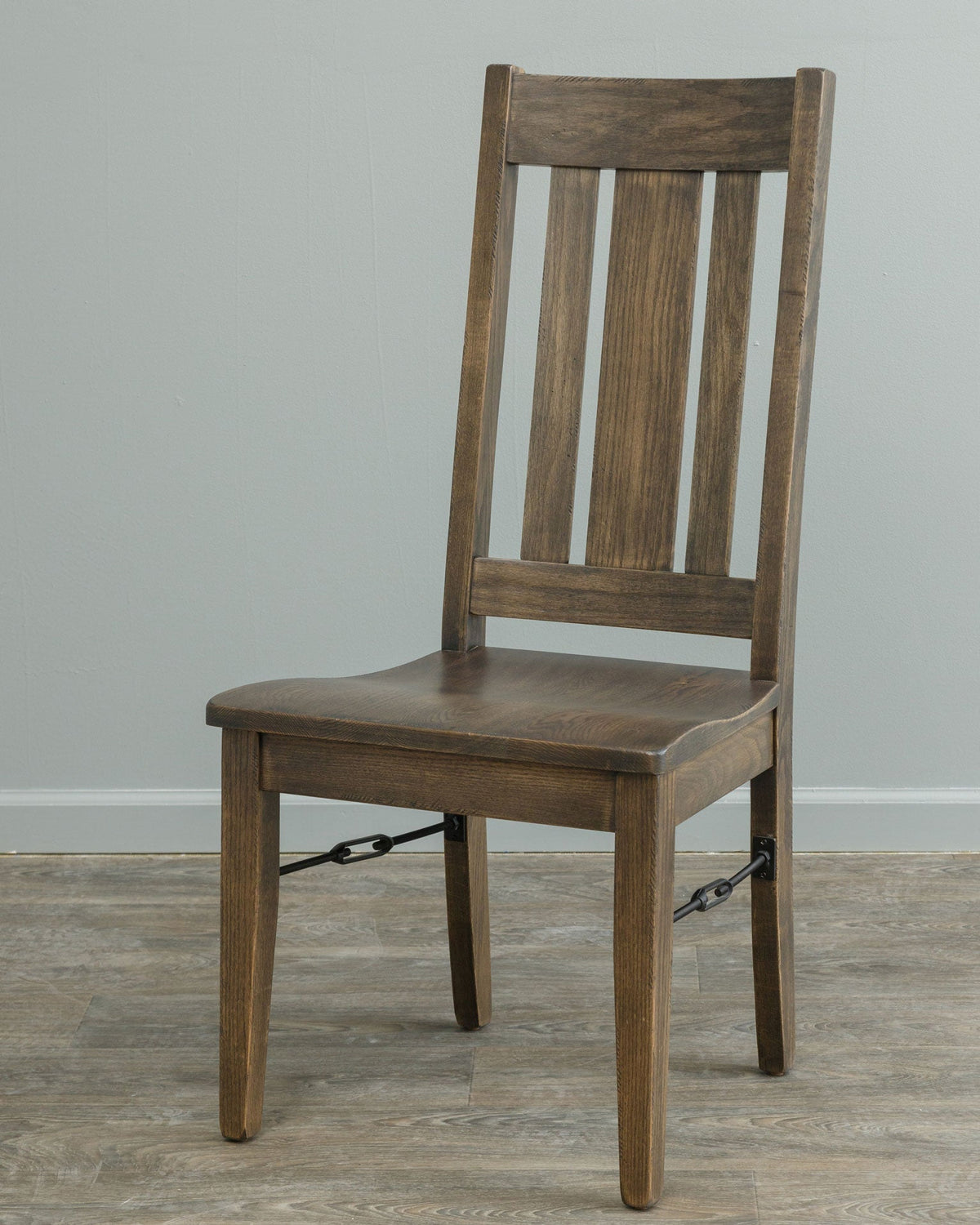 Gray-brown oak dining chair with three back slats, a saddle seat and black iron buckle side stretchers