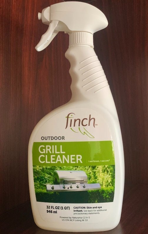 White 32 ounce spray bottle of outdoor grill cleaner with a green label, standing on a wood surface