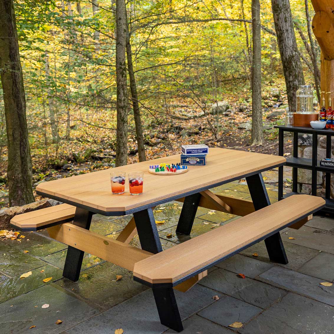 Cedar and black poly picnic table with attached benches on a flagstone patio in an autumn wood